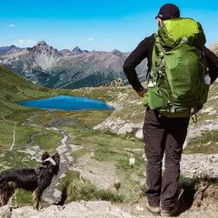 Un randonneur et son chien contemplent un lac bleu et des montagnes majestueuses. Une belle randonnée avec chien.