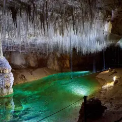 Émerveillement dans la grotte de Thaïs : stalactites fines comme des fils, eau émeraude et formations rocheuses spectaculaires.