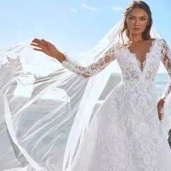 Une mariée sur une plage de sable noir, sa robe en dentelle et son voile flottant au vent, comme une cascade du voile de la mariée.