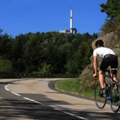 Cycliste en ascension vers le col de l'Oeillon, avec une tour de télécommunication visible au sommet.