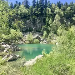 Un paisible lac bleu en Haute-Loire, entouré de rochers et d'une forêt verdoyante.