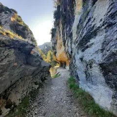 Sentier rocailleux serpentant entre les falaises imposantes des gorges de Trévans. Le soleil perce à travers la roche, illuminant le chemin.