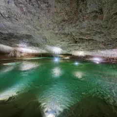 Magnifique lac souterrain aux eaux émeraude, entouré de stalactites, une invitation à **aller aux grottes de Choranche**.