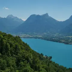 Vue panoramique du lac d'Annecy, ses eaux turquoise bordées de montagnes verdoyantes. Idéal pour un tour du lac Annecy en km.