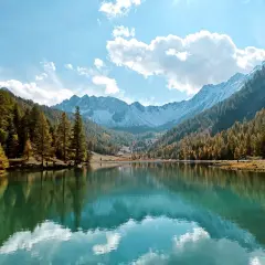 Le lac de l'Orceyrette, miroir des montagnes enneigées et des forêts d'automne, sous un ciel bleu éclatant.