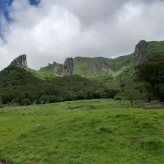 Paysage montagneux verdoyant avec des formations rocheuses spectaculaires. Un panneau indique "Fond de vallée", peut-être le chemin vers la cascade de la biche.