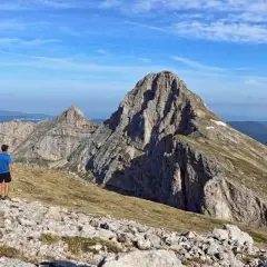 Un randonneur admire la majesté de la grande moucherolle, un pic rocheux imposant sous un ciel bleu.
