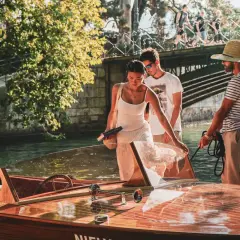 Couple profitant d'une activité à Annecy, embarquant sur un bateau en bois.