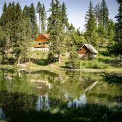 Reflets parfaits des chalets et des sapins dans le lac du Poursollet, un paysage de montagne paisible.