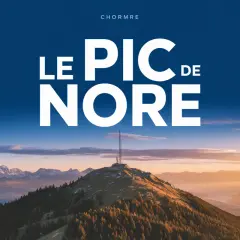 Le pic de Nore, sommet majestueux sous un ciel bleu, dominé par une antenne. Paysage montagneux au coucher du soleil.