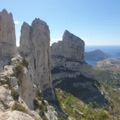 Vue spectaculaire depuis le pas de la demi lune, avec des falaises calcaires imposantes dominant la mer Méditerranée et un village côtier.