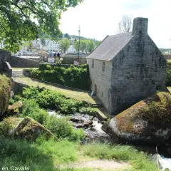 Un ancien bâtiment en pierre près d'un ruisseau, avec des rochers moussus. On dirait la grotte du diable, un lieu mystérieux.