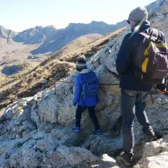 Deux randonneurs escaladent un sentier rocheux près du pic de Morgon, profitant d'une vue imprenable sur les montagnes.