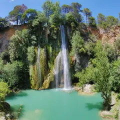 La cascade de Sillans, un spectacle naturel impressionnant, se jette dans un bassin d'eau turquoise entouré de verdure luxuriante.