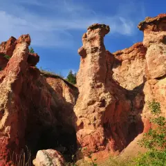 Les formations rocheuses ocreuses de la vallée des Saints en Auvergne, sculptées par le temps, se dressent sous un ciel bleu éclatant.