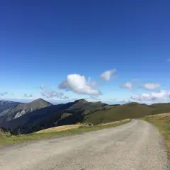 Route sinueuse menant au port de Bales, traversant des paysages de montagnes verdoyantes sous un ciel bleu éclatant.