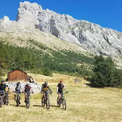 Groupe de cyclistes explorant le col de Gleize, avec une imposante montagne en arrière-plan.