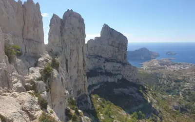 Vue spectaculaire depuis le pas de la demi lune, avec des falaises calcaires imposantes dominant la mer Méditerranée et un village côtier.
