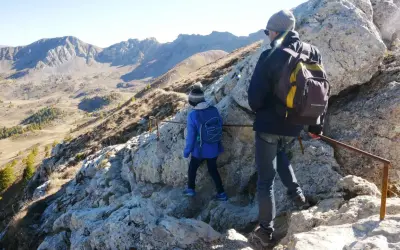 Deux randonneurs escaladent un sentier rocheux près du pic de Morgon, profitant d'une vue imprenable sur les montagnes.