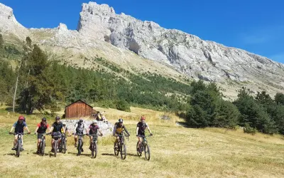 Groupe de cyclistes explorant le col de Gleize, avec une imposante montagne en arrière-plan.