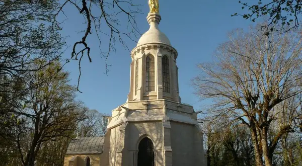Chapelle de Notre-Dame d'Afrique à Dijon, dominée par une statue dorée. Un lieu de quiétude au cœur de la nature.