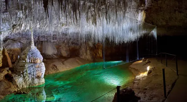 Émerveillement dans la grotte de Thaïs : stalactites fines comme des fils, eau émeraude et formations rocheuses spectaculaires.