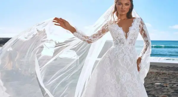 Une mariée sur une plage de sable noir, sa robe en dentelle et son voile flottant au vent, comme une cascade du voile de la mariée.