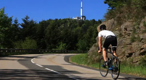 Cycliste en ascension vers le col de l'Oeillon, avec une tour de télécommunication visible au sommet.