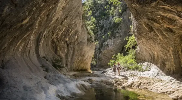 Deux randonneurs explorent les formations rocheuses spectaculaires des concluses de Lussan, un paysage naturel impressionnant.