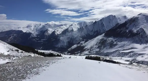 Vue panoramique depuis le col du Soulor, montagnes enneigées sous un ciel bleu et nuageux.