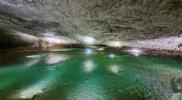 Magnifique lac souterrain aux eaux émeraude, entouré de stalactites, une invitation à **aller aux grottes de Choranche**.