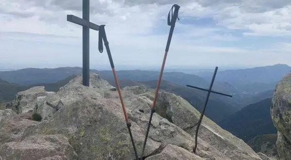 Sommet du pic des 3 Seigneurs. Deux croix et des bâtons de randonnée sur un rocher, avec une vue panoramique sur les montagnes.