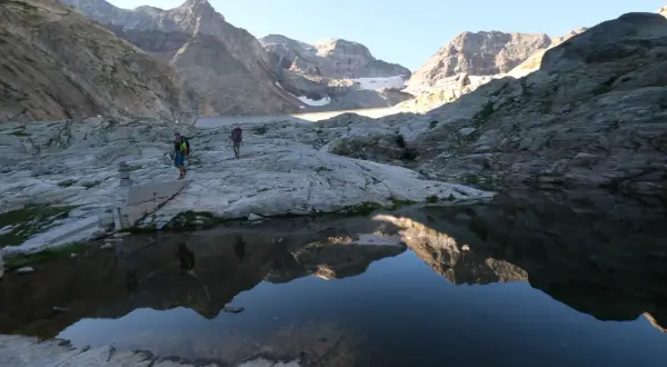 Randonneurs traversant un paysage rocheux près du lac du Portillon, avec des montagnes imposantes en arrière-plan.