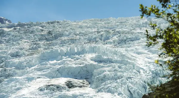 Vaste étendue de glace craquelée et texturée du glacier des Bossons sous un ciel bleu clair.