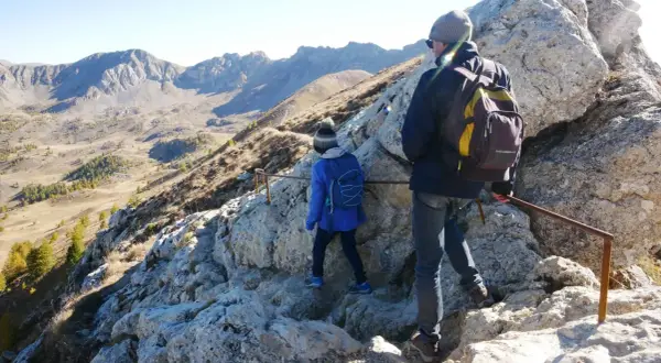 Deux randonneurs escaladent un sentier rocheux près du pic de Morgon, profitant d'une vue imprenable sur les montagnes.