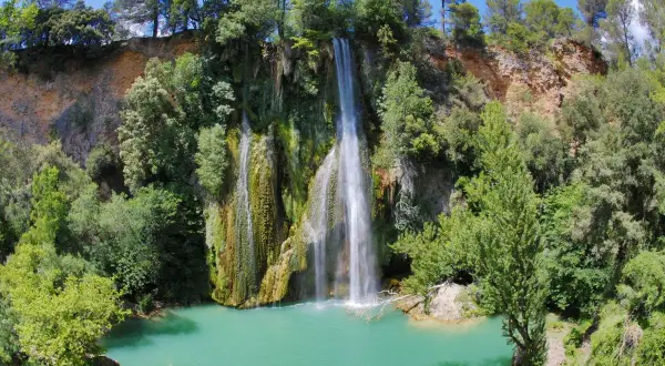 La cascade de Sillans, un spectacle naturel impressionnant, se jette dans un bassin d'eau turquoise entouré de verdure luxuriante.