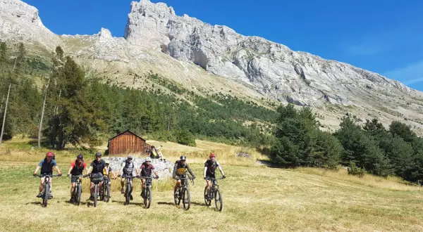 Groupe de cyclistes explorant le col de Gleize, avec une imposante montagne en arrière-plan.