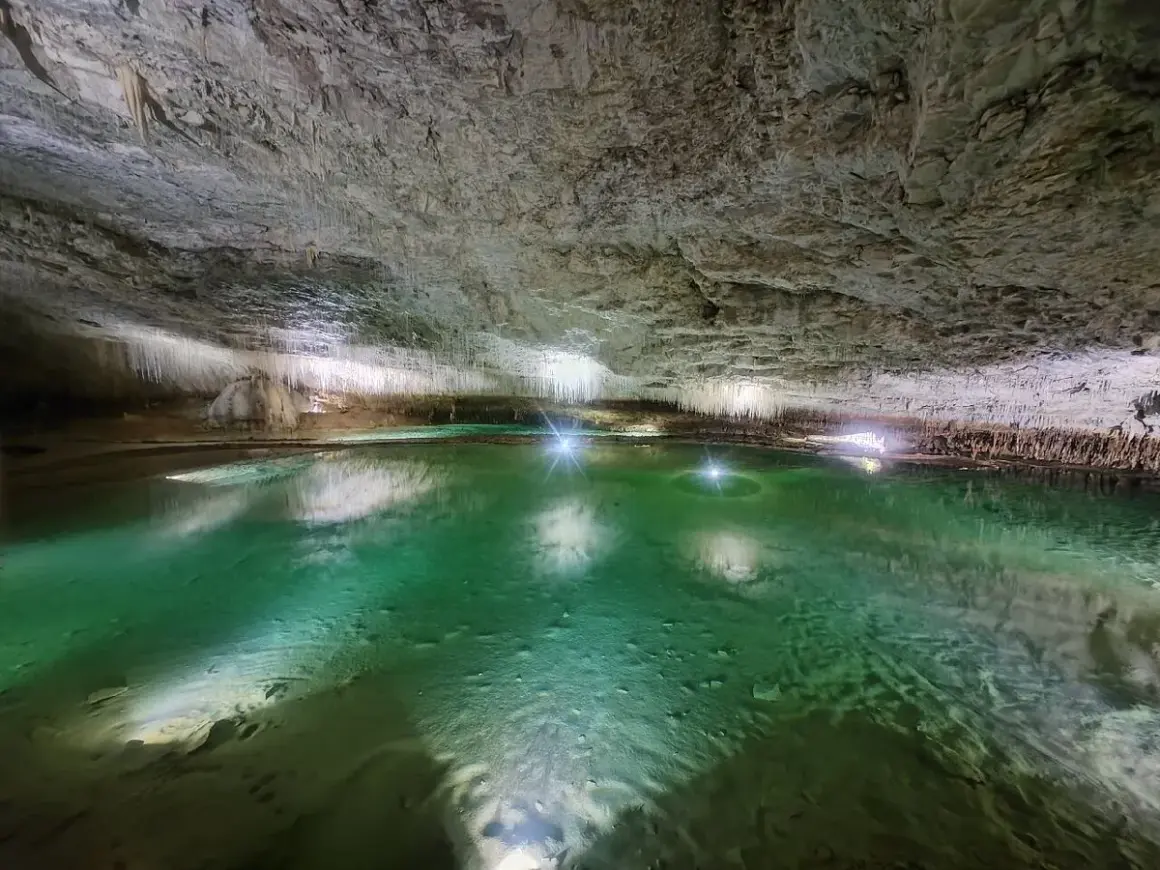 Magnifique lac souterrain aux eaux émeraude, entouré de stalactites, une invitation à **aller aux grottes de Choranche**.