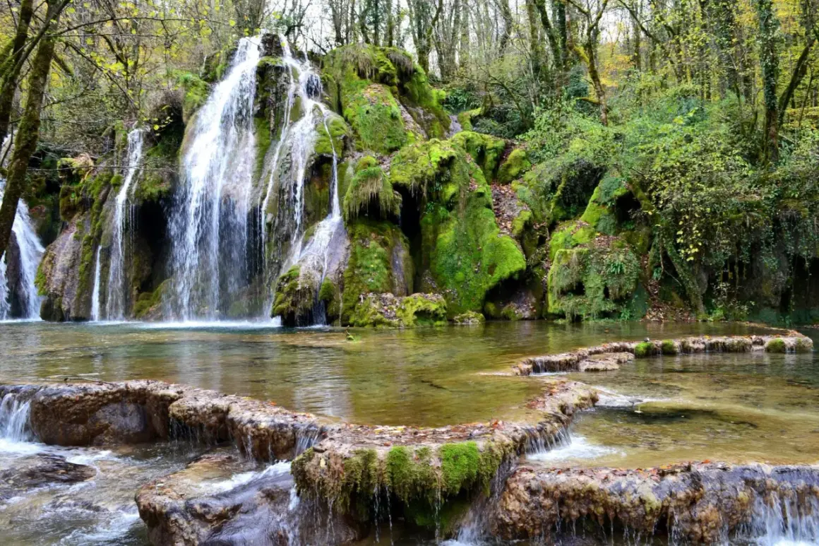 La cascade des tufs, un spectacle naturel verdoyant où l'eau tombe en voiles sur des roches moussues, créant un paysage enchanteur.