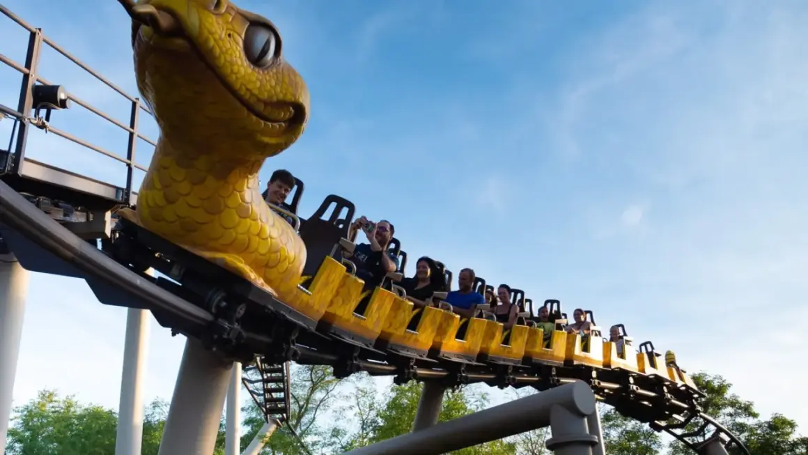 Un train de montagnes russes en forme de serpent jaune emmène des passagers joyeux dans le ciel bleu. Une idée pour que faire ce dimanche dans le 43 ?