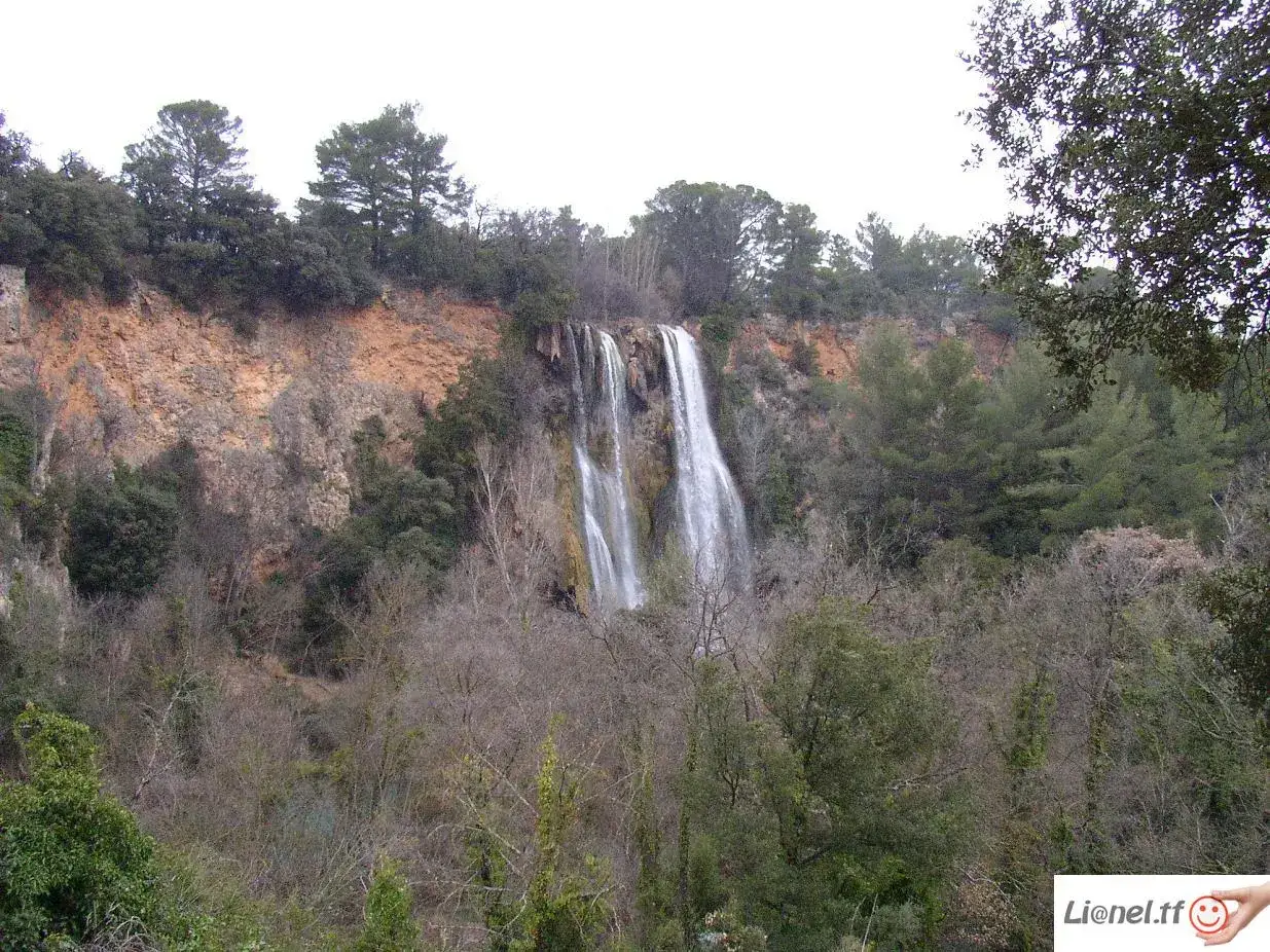 Magnifique cascade pr&egrave;s de Gr&eacute;oux-les-Bains, tombant d'une falaise ocre, entour&eacute;e d'une v&eacute;g&eacute;tation dense et d'arbres d&eacute;nud&eacute;s.