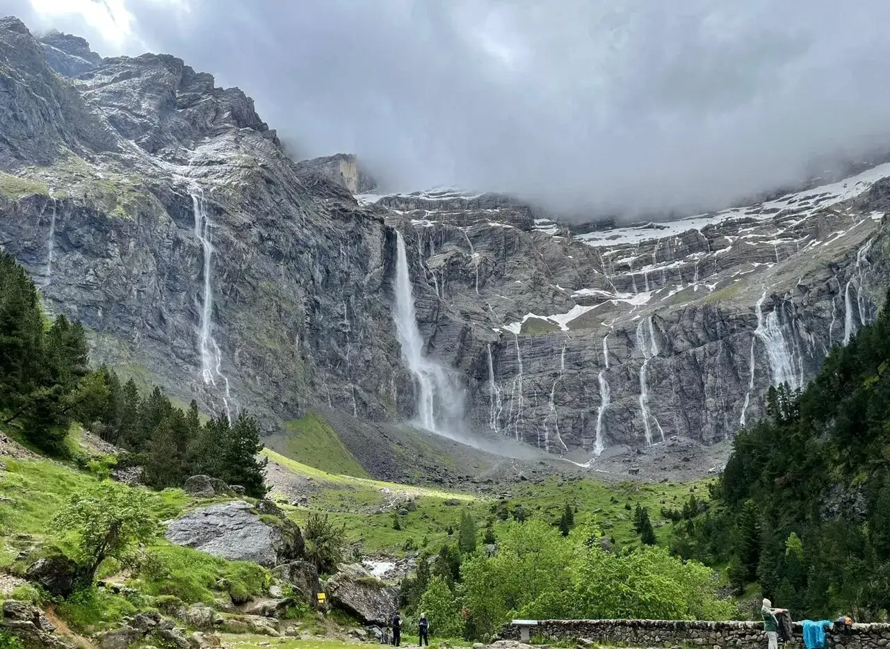 Le cirque de Gavarnie, un amphithéâtre naturel de falaises rocheuses, est orné de nombreuses cascades tombant dans une vallée verdoyante.