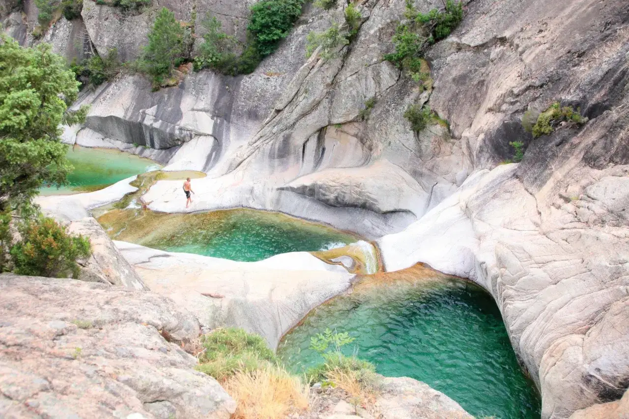 Un homme profite d'une cascade piscine naturelle en Ard&egrave;che, entour&eacute; de roches sculpt&eacute;es par l'eau.