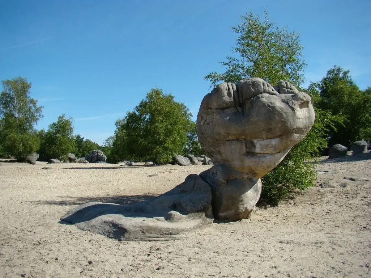 Un rocher sculpté par le temps, tel un géant endormi, dans le paysage sablonneux du massif des Trois Pignons.