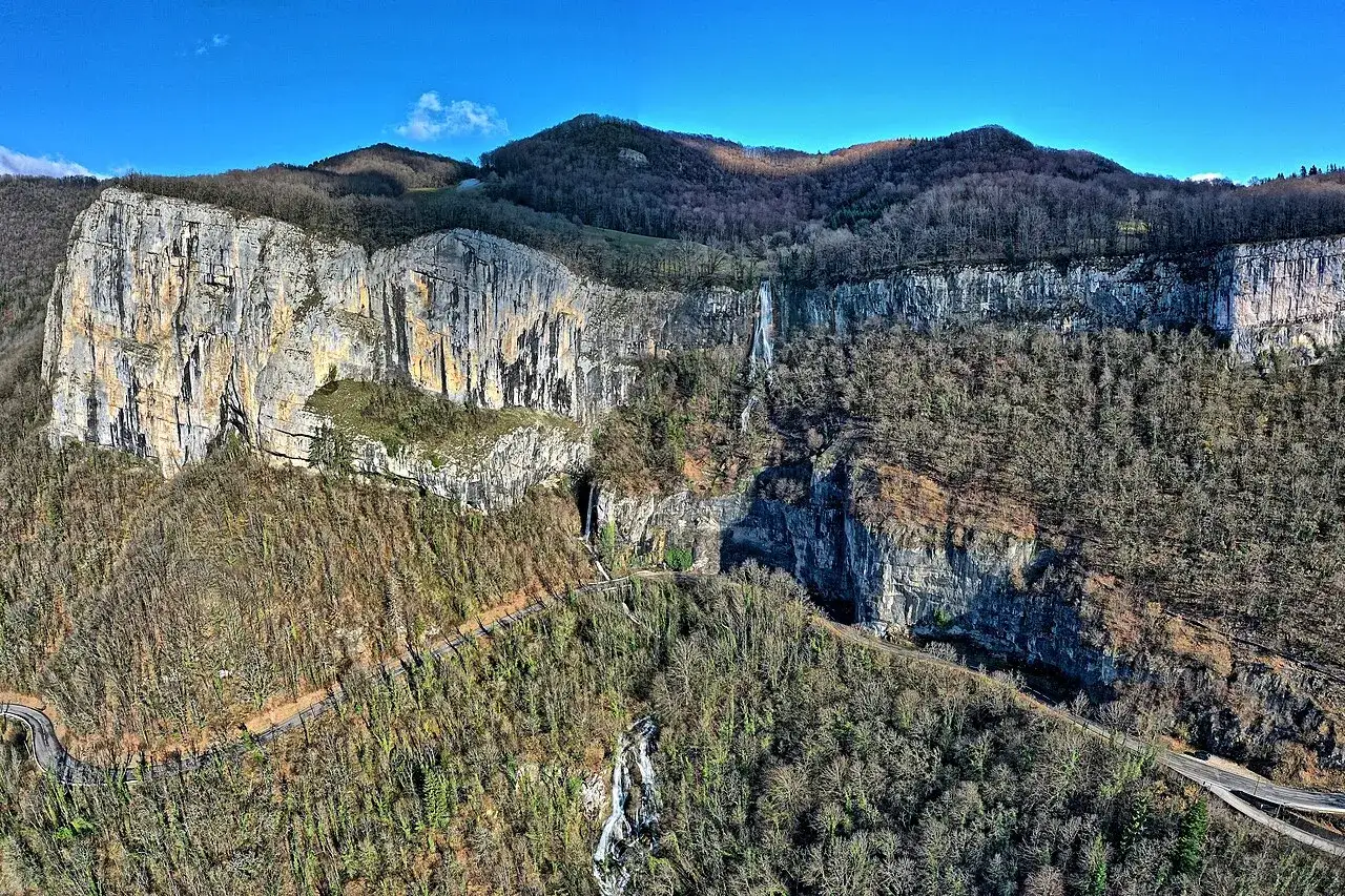 Vue a&eacute;rienne de la cascade de Syratus, impressionnante chute d'eau tombant d'une falaise rocheuse, entour&eacute;e de for&ecirc;ts denses.