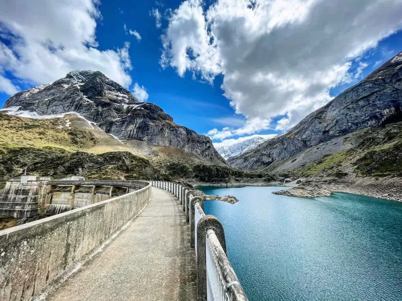 Vue panoramique du lac des gloriettes, un lac d'un bleu profond entouré de montagnes imposantes et d'un barrage imposant.