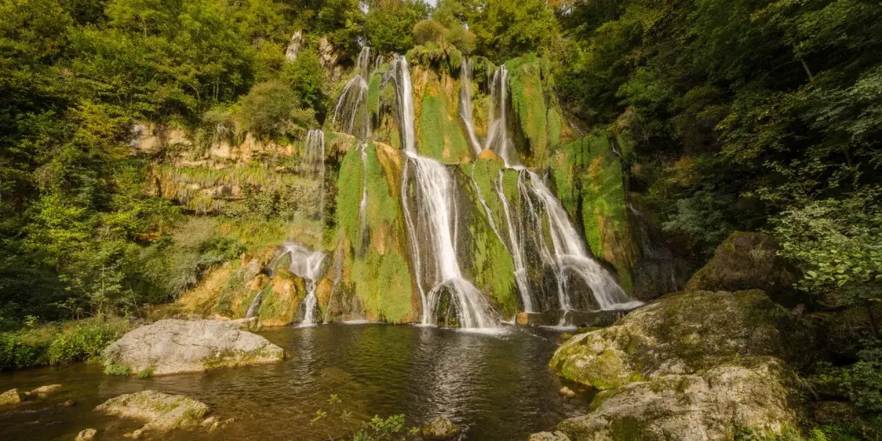 La cascade de Glandieu d&eacute;vale une falaise verdoyante, ses eaux se jetant dans un bassin paisible. Un spectacle naturel saisissant.