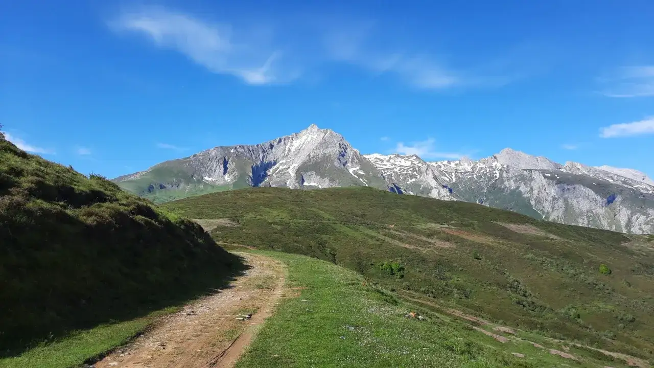 Sentier rocailleux menant au col du Soulor, avec des montagnes enneig&eacute;es en arri&egrave;re-plan sous un ciel bleu &eacute;clatant.
