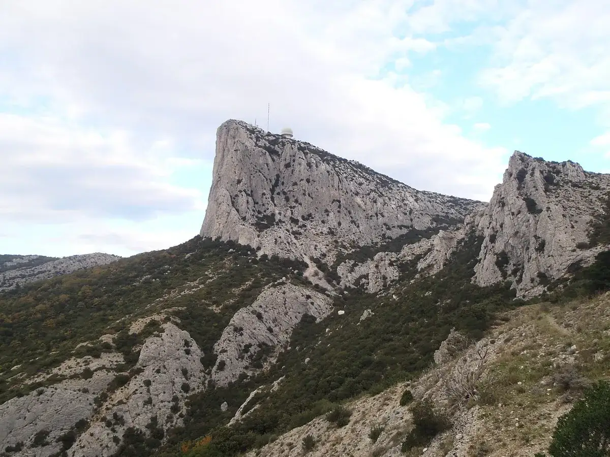 Vue panoramique du pic de Bertagne, un sommet rocheux imposant couvert de végétation.