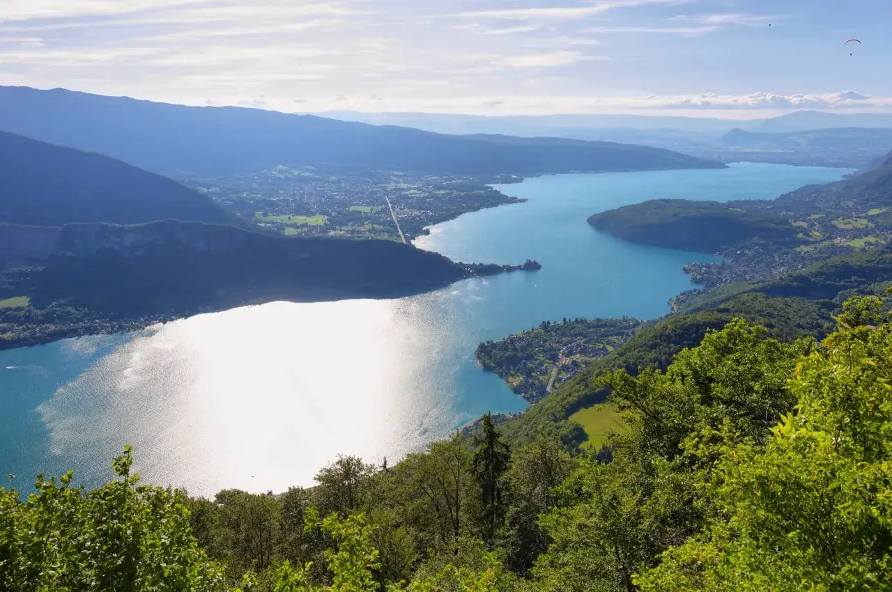 Vue panoramique sur le lac d'Annecy, ses eaux bleues scintillantes et les montagnes environnantes. La taille du lac d'Annecy est impressionnante.